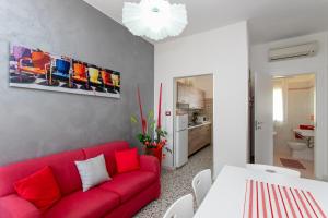 a living room with a red couch and a table at Appartamenti Bedin, JESOLO LIDO in Lido di Jesolo