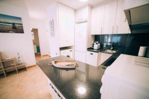 kuchnia z białymi szafkami i czarnym blatem w obiekcie Apartamento reformado en Calella de Palafrugell a 1 minuto de la playa w mieście Calella de Palafrugell