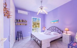 a purple bedroom with a bed and a window at Monolithi Seaside Cottage in Kanali