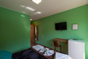 a bedroom with green walls and a bed and a desk at Pousada Zero Grau in Nova Friburgo