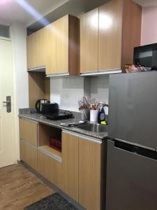a kitchen with wooden cabinets and a stainless steel refrigerator at Travelers Delight Amani Grand Resort Residences 3-5mins from airport in Mactan
