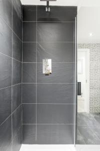 a bathroom with a shower with black tiles at cozy stay in Birmingham by the Canal !! in Birmingham +20 photos