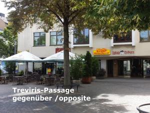 a building with tables and umbrellas in front of it at Ferienwohnung VISHWAS in Trier