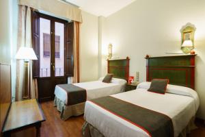 um quarto de hotel com duas camas e uma janela em Hotel Plaza Nueva em Granada