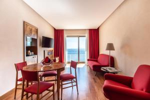 uma sala de estar com cadeiras vermelhas e uma mesa e um quarto com uma janela em Hotel Royal Continental em Nápoles