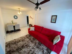a red couch in a living room with a table at Alto Padrão com 94 mtrs - Frente Mar - sacada com Vista Mar in Praia Grande