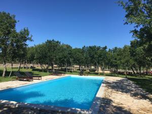 a swimming pool in a park with benches and trees at Micanovi Dvori Mobile Home Village Zrmanja in Obrovac