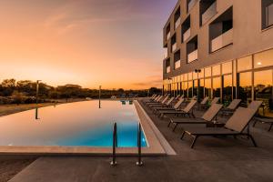 a pool with lounge chairs in front of a building at Hotel Olea in Novalja