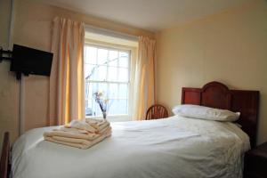 um quarto com uma cama com lençóis brancos e uma janela em The Sun Inn em Dent