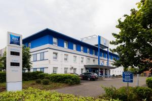 un edificio azul y blanco con un coche aparcado delante en ibis budget Köln Marsdorf en Colonia