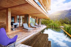 a wooden deck with chairs and a swimming pool at ZillerLodge in Uderns