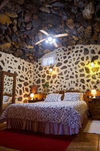 a bedroom with a bed and a stone wall at Amazing Country House with Ocean View, Cueva de la Arena in Garachico