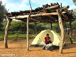 a man sitting inside of a tent in the dirt at Camping agreste El Algarrobo de Quilmes in Amaichá del Valle