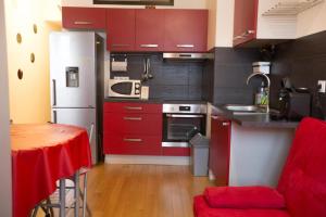 cocina con armarios rojos, mesa y nevera en Location F3 Fontenay-Aux-Roses, en Fontenay-aux-Roses