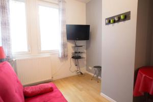 a living room with a red couch and a tv at Location F3 Fontenay-Aux-Roses in Fontenay-aux-Roses