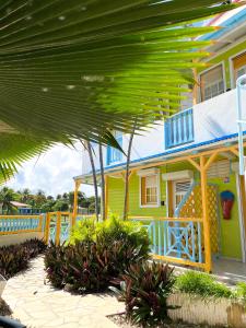 a yellow and blue house with a large green roof at Hotel Oasis in Grande Anse