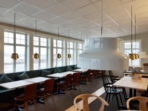 a restaurant with tables and chairs and a large chandelier at Cape East in Haparanda