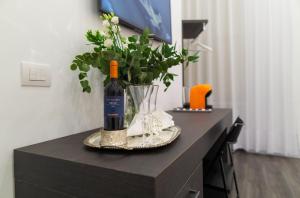 una botella de vino y un jarrón de flores sobre una mesa en Suite Rodinò 24, en Nápoles