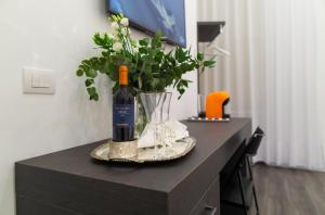 a bottle of wine and a vase of flowers on a table at Suite Rodinò 24 in Naples