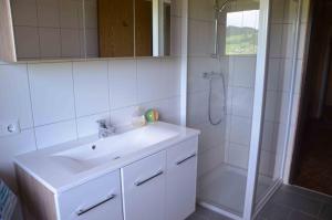 biała łazienka z umywalką i prysznicem w obiekcie Ferienhaus Mitterbauer w mieście Oberhofen am Irrsee