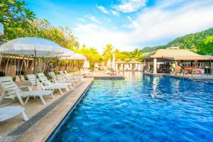 a swimming pool with white chairs and umbrellas at Phuket Kata Resotel in Kata Beach