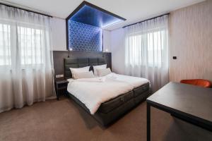 a bedroom with a bed and a desk and windows at premium by GS Hotel in Munich +44 photos