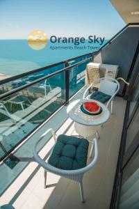 a balcony with a table and chairs and the ocean at Orange Sky Apartments Beach Tower in Batumi