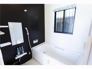 uma casa de banho com uma banheira branca e um espelho. em Kabuku Resort em Shima