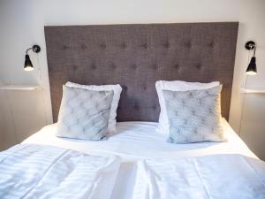 a white bed with two pillows and a large headboard at Hotel Residens Møen in Stege