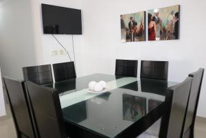 comedor con mesa de cristal y sillas negras en Apartamento Amueblado Amplio Tranquilo Privado Como tu lo Mereces en Santiago de los Caballeros