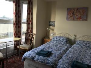 a bedroom with a bed and a table and a window at Bayside Guest House in Porthcawl