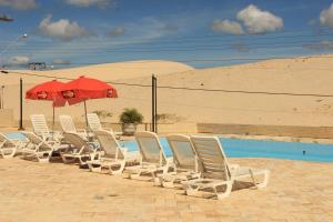 佛羅安那波里的住宿－Via Praia Apart Hotel，游泳池旁的一排椅子和一把遮阳伞