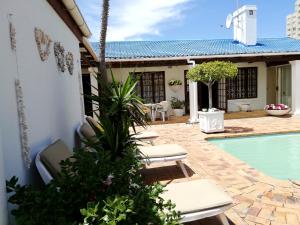 a patio with a pool and chairs and a house at Dolphin Inn Blouberg in Bloubergstrand