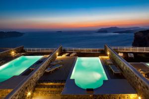 a hotel with two pools and a view of the ocean at Thermes Luxury Villas And Spa in Megalochori