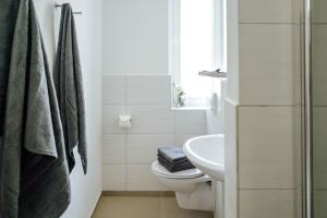 Baño blanco con aseo y lavamanos en Kleines Zimmer an der TA mit Balkon (Nr.3), en Hameln