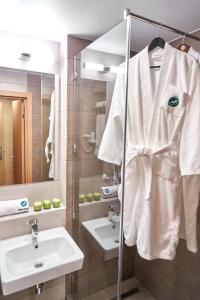 a bathroom with a sink and a robe at Congress Hotel Malakhit in Chelyabinsk