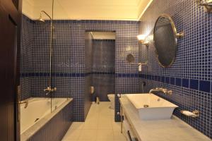 a bathroom with blue tiled walls and a tub and a sink at Hotel Casa Higueras in Valparaíso