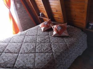 Una cama con dos almohadas encima. en Cabañas Alpinas Terra Natura en Bialet Massé