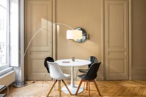 a dining room with a white table and black chairs at Honorê - Suite Barre in Lyon