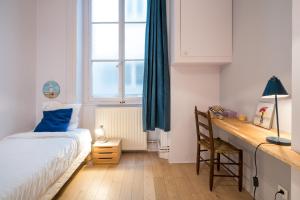 a bedroom with a bed and a desk and a window at Honorê - Suite Barre in Lyon