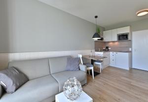 ein Wohnzimmer mit einem Sofa und einer Küche in der Unterkunft Hotel- & Ferienanlage Kapitäns-Häuser Breege in Breege