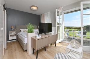 a living room with a television on a desk with a couch at Hotel- & Ferienanlage Kapitäns-Häuser Breege in Breege