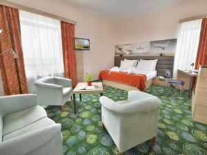 a hotel room with a bed and a couch and chairs at Ramada Airport Hotel Prague in Prague