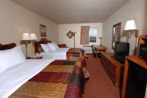a hotel room with two beds and a flat screen tv at All American Inn & Suites Branson in Branson