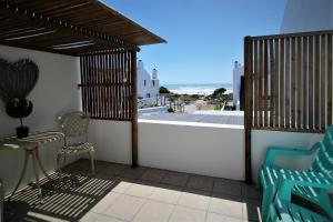 a balcony with a table and chairs and a view of the ocean at Baywatch Guest House in Paternoster