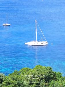 a sailboat floating in the water in the ocean at Résidence Séjourné in Les Anses-dʼArlets