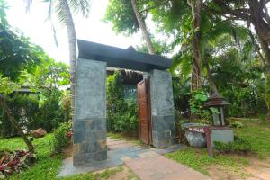 Una pequeña casa con una puerta de madera en un jardín en Zara Beach Resort Koh Samui - SHA Extra Plus Certified, en Lamai
