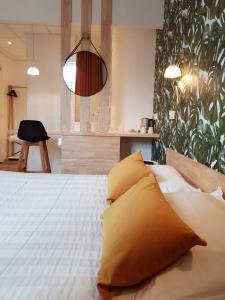 a bedroom with a bed with yellow pillows and a mirror at The Originals Boutique, Grand Hôtel Saint-Pierre, Aurillac in Aurillac