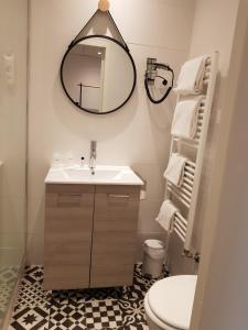 a bathroom with a sink and a mirror and a toilet at The Originals Boutique, Grand Hôtel Saint-Pierre, Aurillac (Qualys-Hotel) in Aurillac