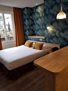a hotel room with a bed and a table at The Originals Boutique, Grand Hôtel Saint-Pierre, Aurillac (Qualys-Hotel) in Aurillac